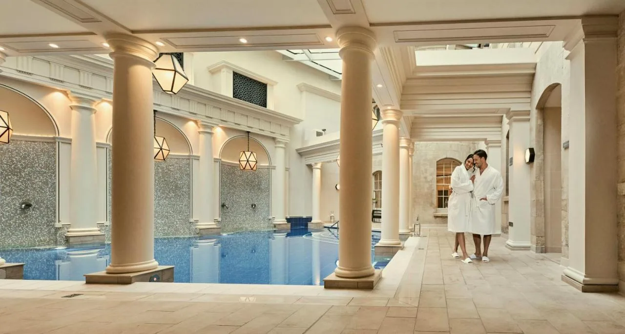 a bride and groom standing in front of a swimming pool at The Gainsborough Bath Spa in Bath