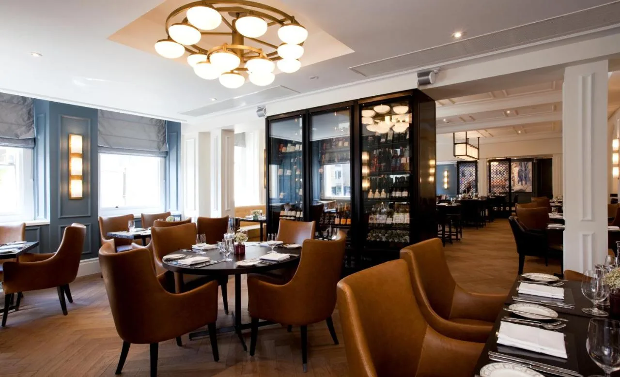 a restaurant with tables and chairs and a chandelier at The Gainsborough Bath Spa in Bath